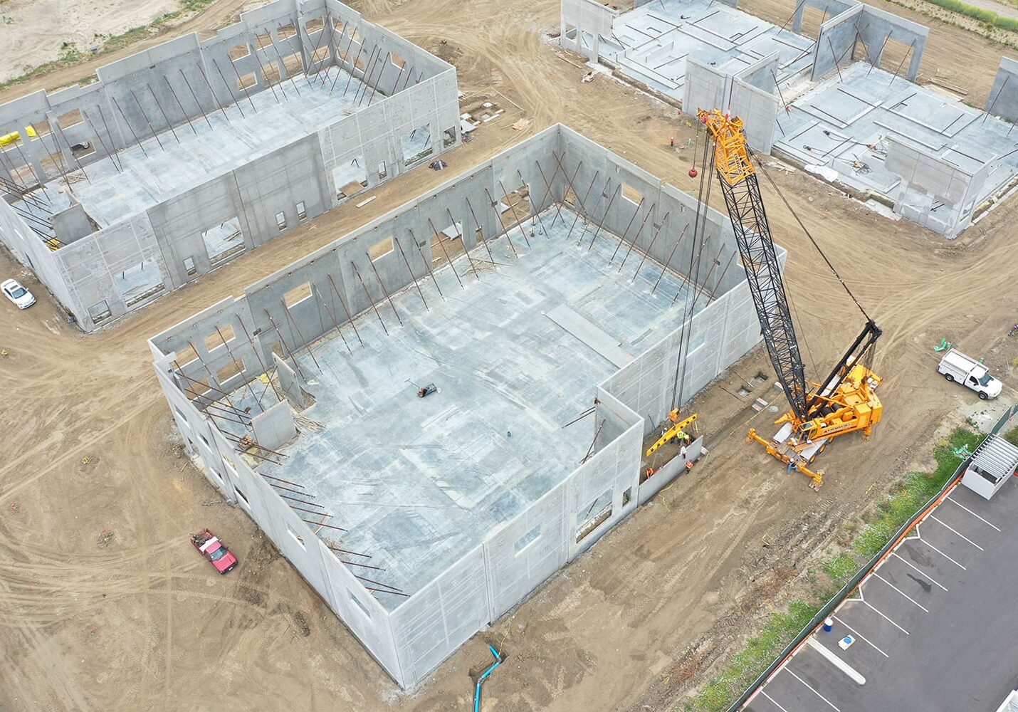 Aerial view of a construction site with large concrete buildings in progress and a yellow crane lifting materials.